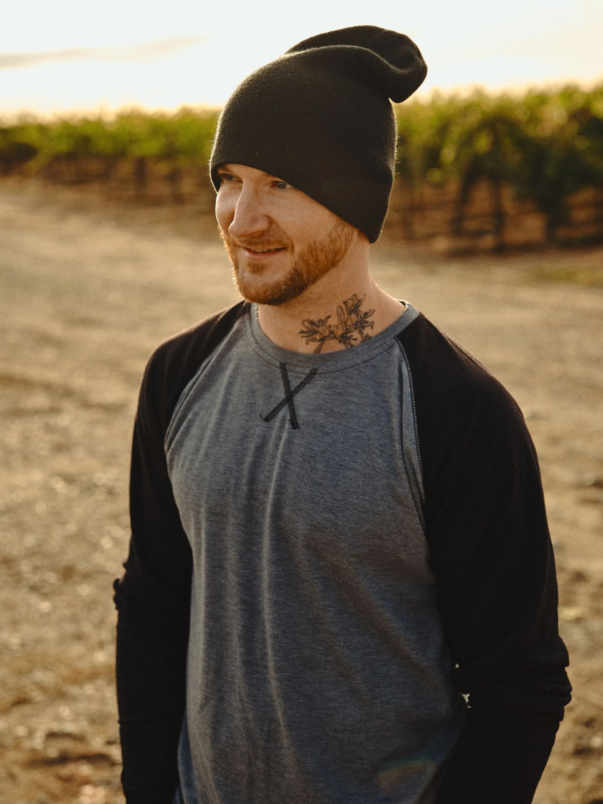 A man wearing a hat standing in a vineyard